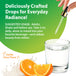 Collagen Biotin Hyal Drops Liquid being dispensed into a glass of water, with oranges & milky splash representing Vanilla Citrus Flavor.